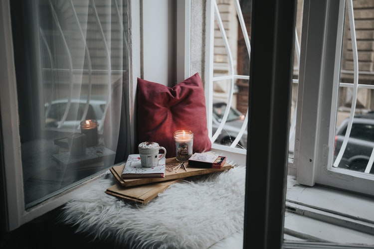 create a cosy window seat to be the envy of your frineds. this is a picture of a cushion on a windowsill with a cuppa and a candle