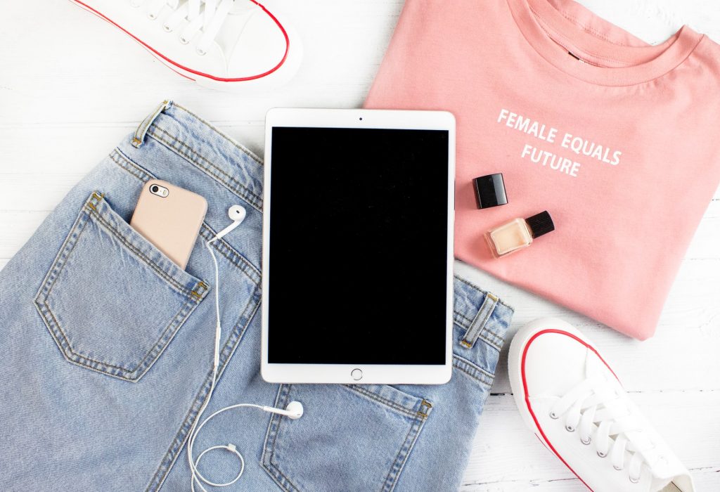 flatlay of pink t shirt, jeansm headphones, ipad