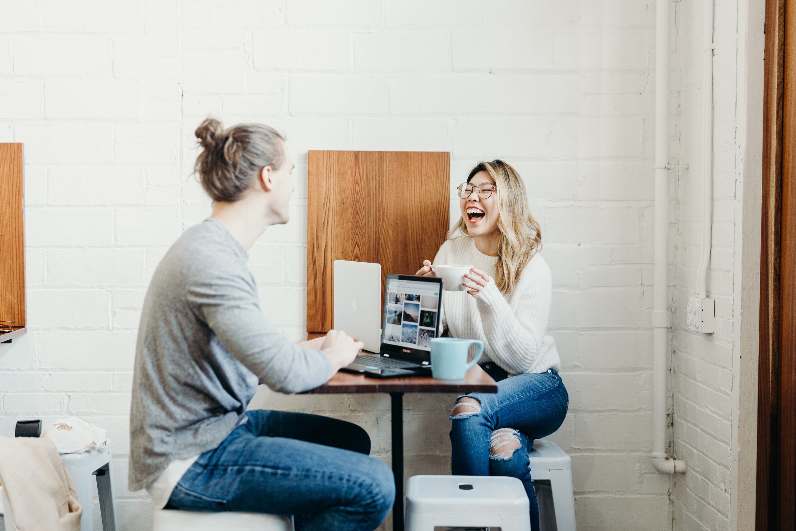 couple at a table iwht computer laughing and enjoying themslves