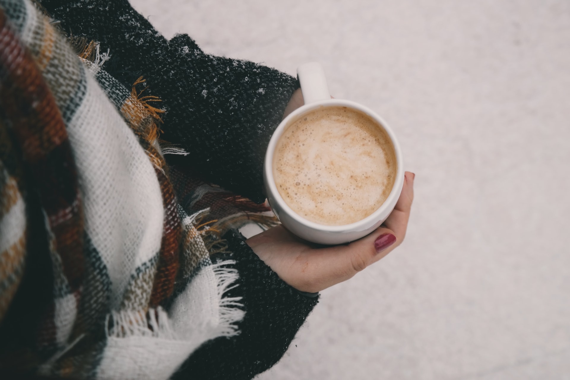 winter blog post ideas - picture of a top down view of women's hands holding a coffee with cool colour scheme