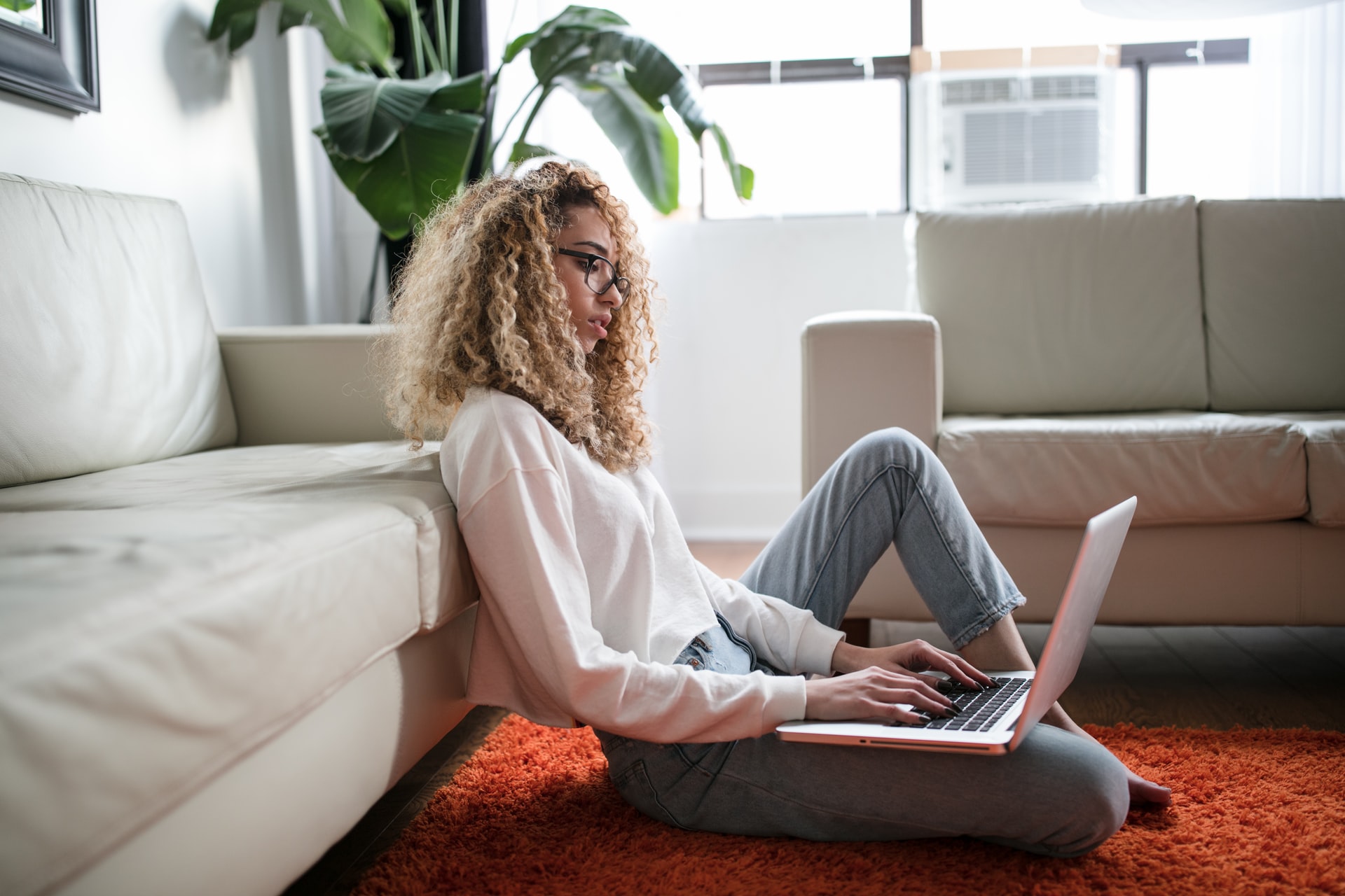woman sitting on floor with laptop on her knee