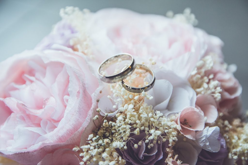 Two wedding rings places on a pink and white wedding bouquet