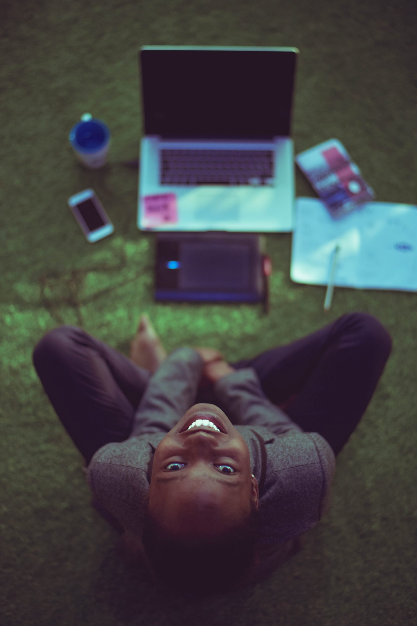 lady sat in front of a laptop, looking up at the camera and smiling