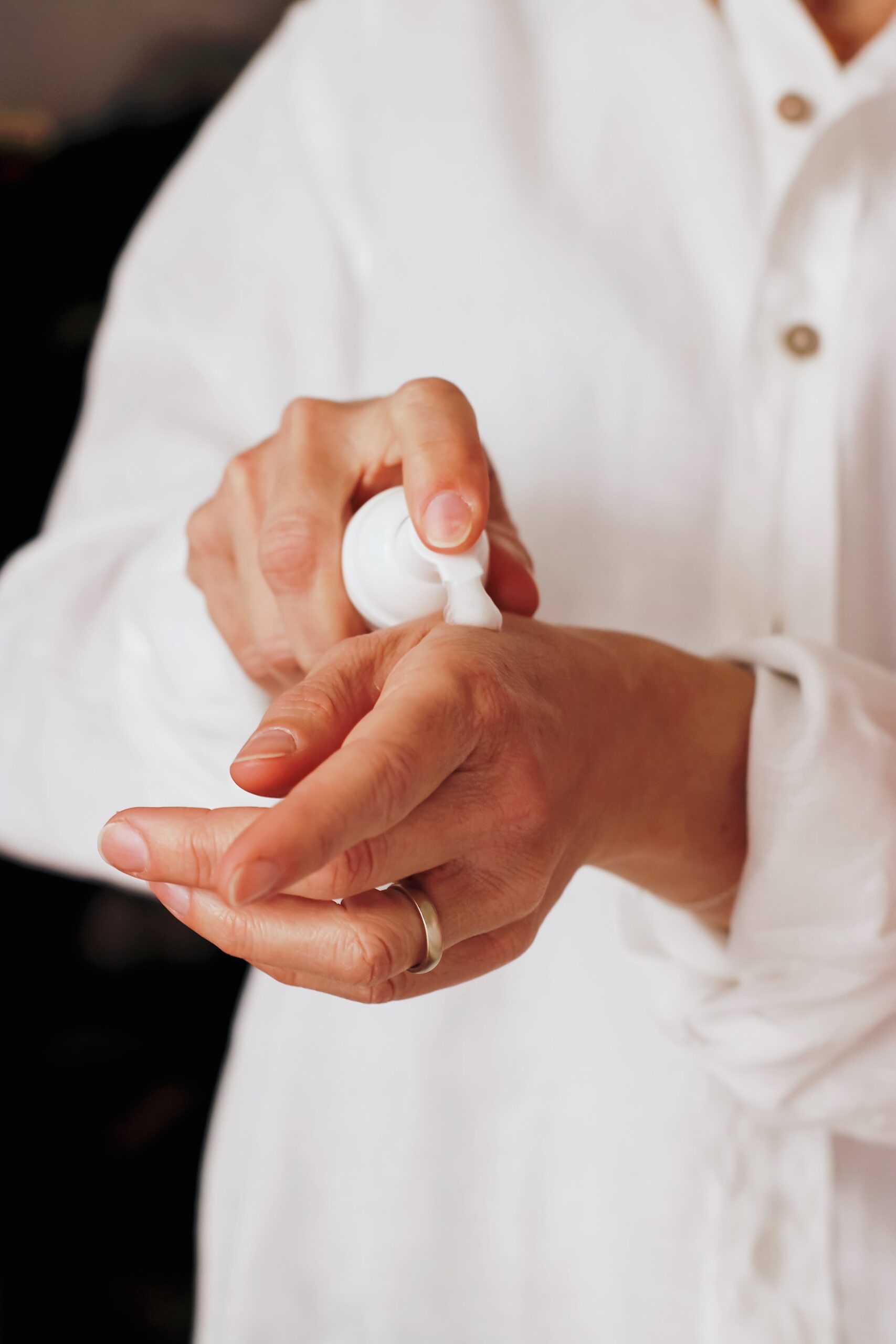 hands applying cream from a pump action bottle