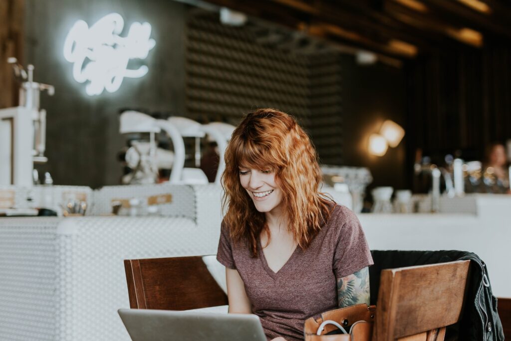 Is friend PC legit? Pic of a red haired lady smiling at her laptop in a coffee shop.